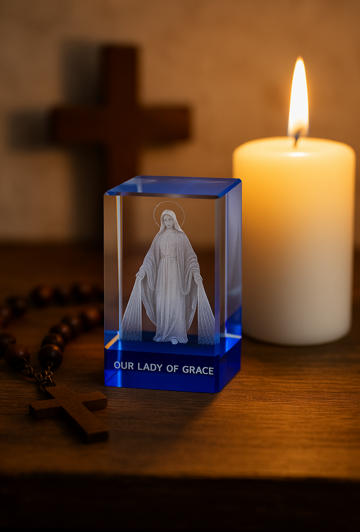 Crystal figurine of Our Lady of Grace with a lit candle and cross in the background