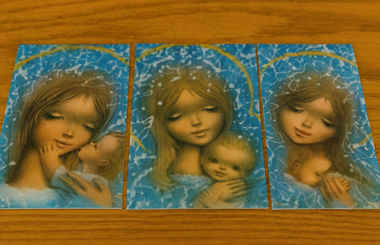 Triptych of a woman holding a baby against a blue watercolor background on a wooden surface.